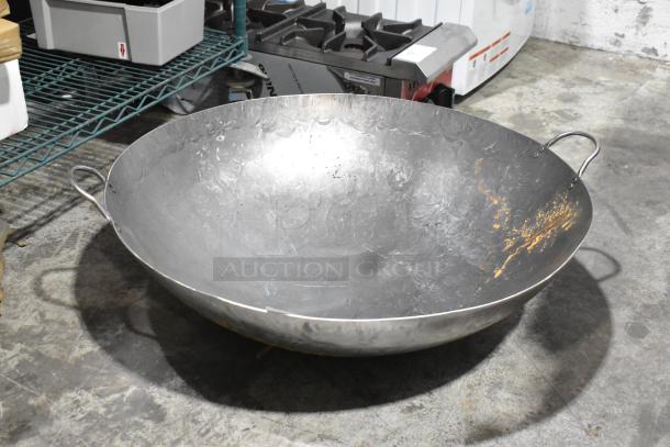Brand new scratch and dent metal wok, large size, slight surface imperfections, sturdy handles, suitable for high-heat cooking.