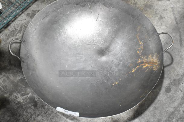 Two brand new metal woks with minor scratches and dents, featuring dual handles; auction tag visible.