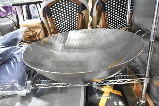 Two brand new metal woks with scratch and dent imperfections. Industrial-style design, ideal for high-heat cooking.