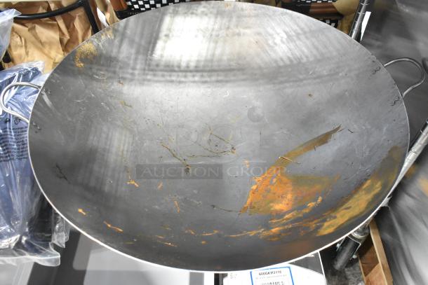 Brand new metal wok with visible scratch and dent markings. Large size, sturdy handles, uncoated finish. Ideal for high heat cooking.