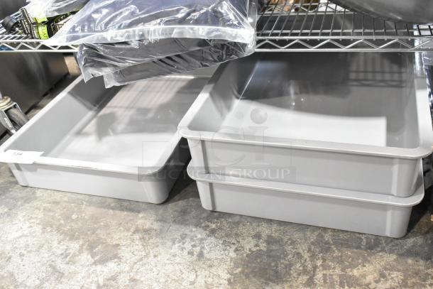 Three brand new gray poly dough bins, slightly scratched and dented, stacked on a warehouse floor.