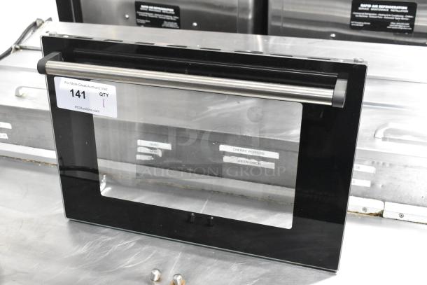 Brand new metal oven door, scratch and dent condition, black frame with stainless steel handle, auction tag visible.