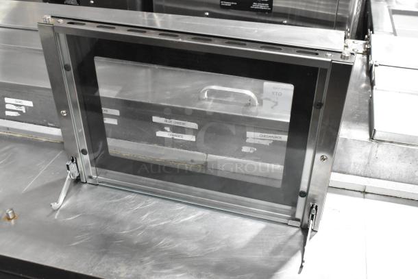 Brand new metal oven door with glass panel, minor scratches and dents visible, sturdy hinges, ideal for replacement.