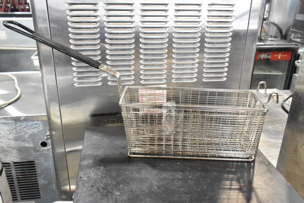 Metal fry basket with black handle, new condition, minor dents visible. Includes warning label and plastic wrap inside.