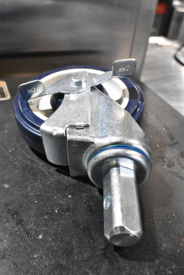 Brand new scratch and dent commercial caster, metallic, swivel design, minor surface imperfections visible.