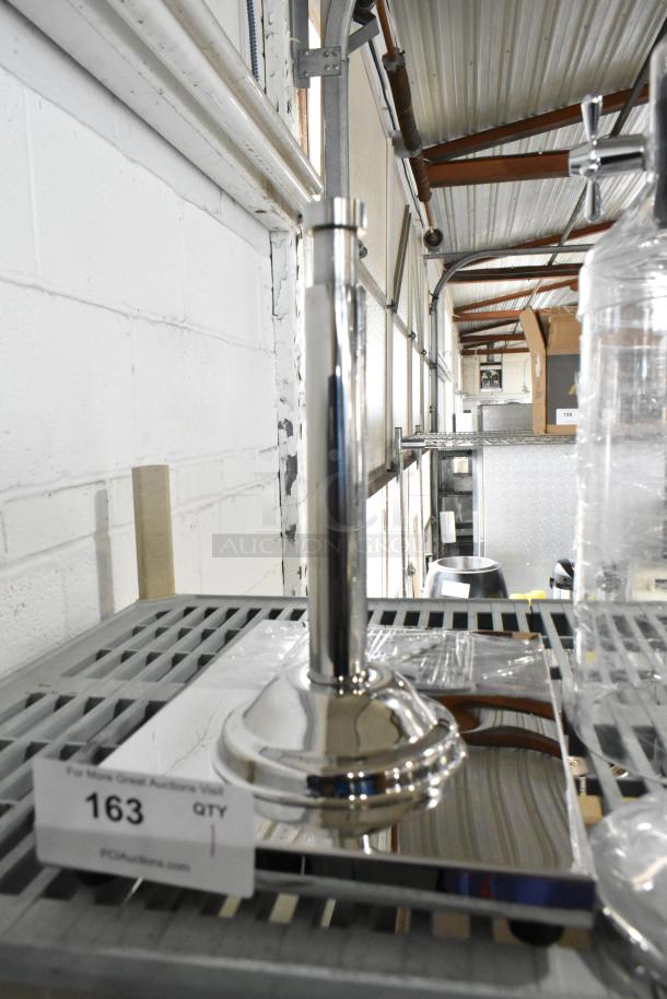 Brand new clear dispenser with a shiny stainless steel base, slight dents visible. Auction lot number 163 displayed.
