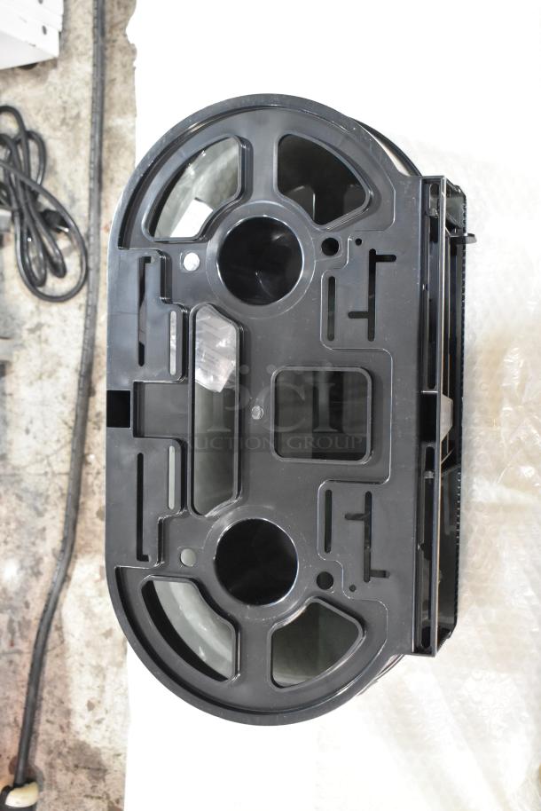 Black poly wall mount toilet paper dispenser, new condition, with minor scratches and dents, ready for installation.