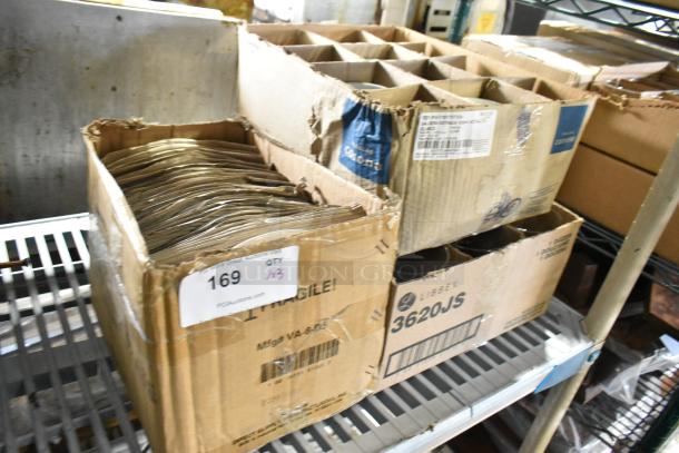 Three boxes of new scratch and dent items: E0583 plates, Corona ramekins, Libbey 3620JS glasses. Boxes labeled with product details.