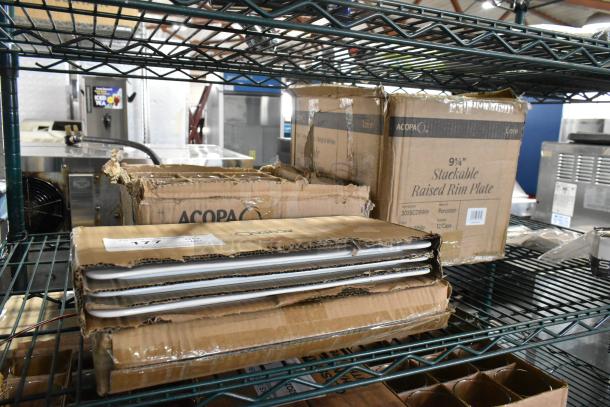 Boxes of Acopa items, including 12 oz. stemless wine glasses and 9 1/4" raised rim porcelain plates, on metal shelving.