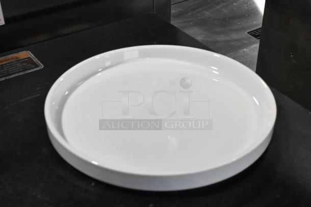 Acopa Lore 9.25" Bright White Raised Rim Porcelain Plate, brand new, on dark surface, in pristine condition.