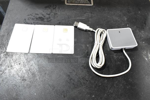 Three smart cards and a USB-connected gray reader on a black surface, part of the TurboChef CON-7006 Chefcomm Pro set.