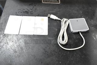 Three smart cards and a USB-connected gray reader on a black surface, part of the TurboChef CON-7006 Chefcomm Pro set.