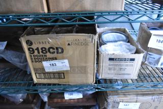 Boxes of Libbey 918CD heavy base glasses and GET Enterprises CS-610-DG plates on a shelf. Includes auction tags.