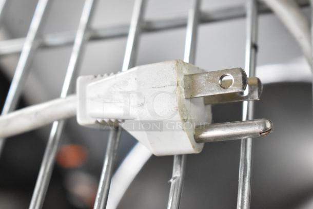Close-up of a white electrical plug connected to a metal frame, possibly part of the Sam4S ER-521SM Cash Register setup.
