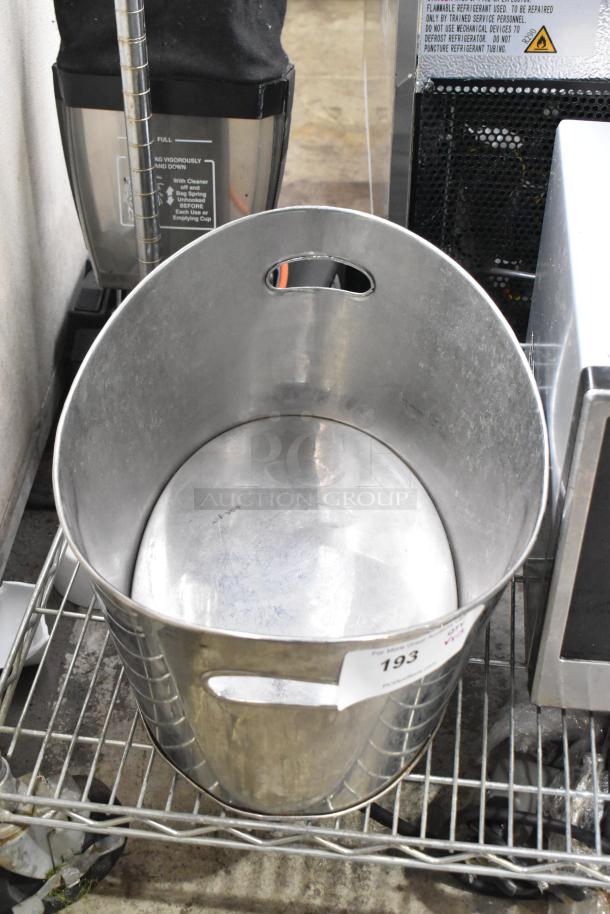 Alt Text: Metal ice bucket with cutout handles, placed on a wire shelf, shows moderate wear; auction label reads "193".