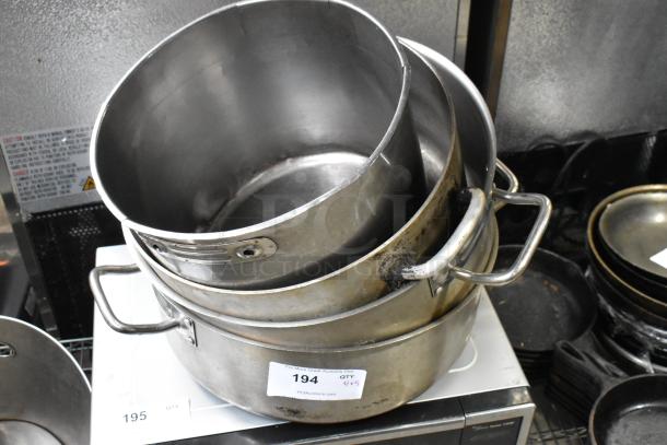 Five metal stock pots in various sizes with handles, showing signs of wear. Number label "194 QTY 5" visible.