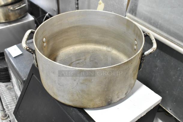 Worn metal stock pot with dual handles, showing signs of heavy use. Part of a set of 5 similar pots for auction.