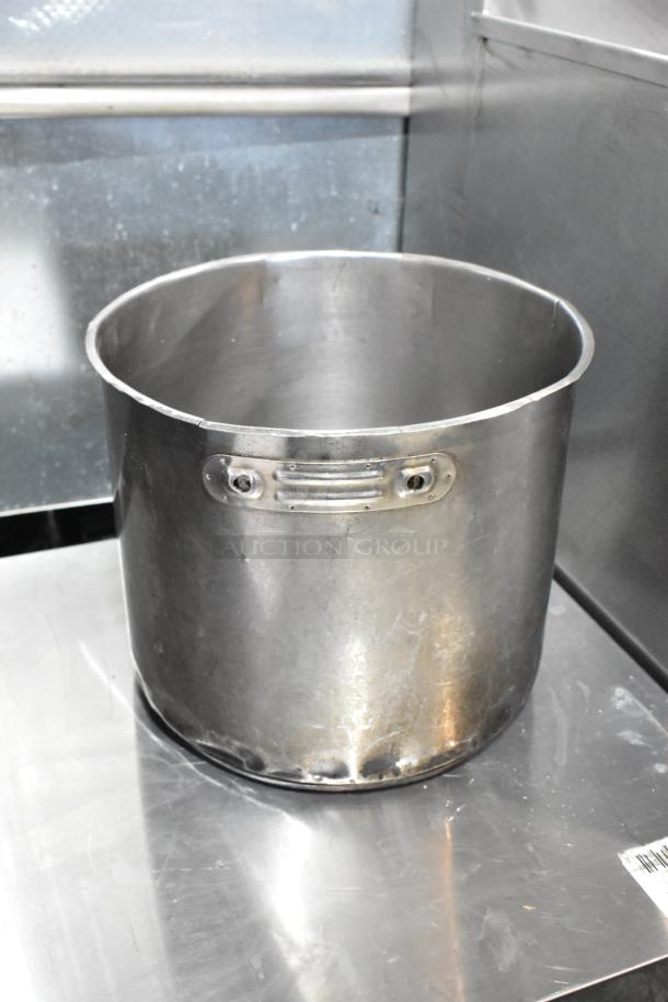 Large metal stock pot with handles, showing wear and scuffs. Part of a lot of 5; ideal for bulk cooking needs.