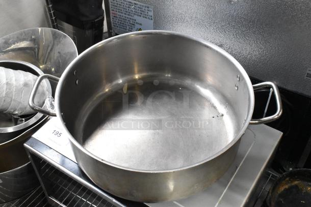 Five assorted metal stock pots with sturdy handles, suitable for large-scale cooking. Visible wear; auction lot 195.