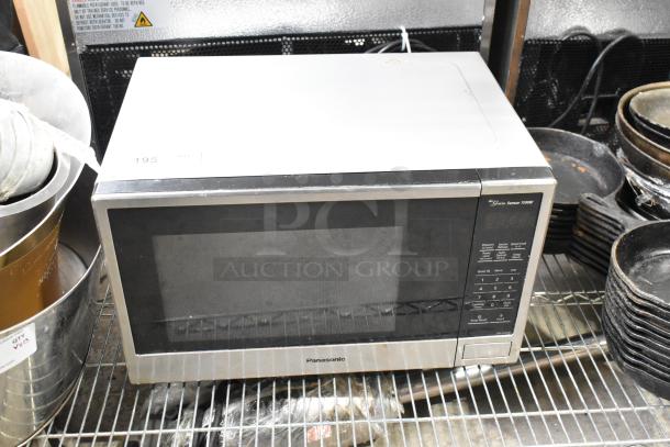 Panasonic NN-SU696S countertop microwave oven with control panel, plate, 115 Volts. Appears gently used on metal shelf.