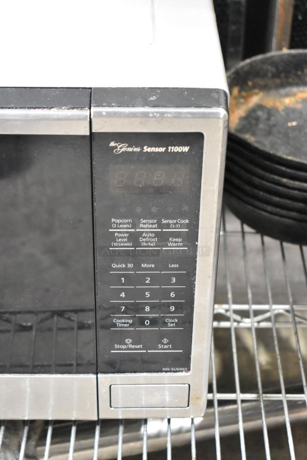 Panasonic NN-SU696S microwave oven, 1100W, black and stainless steel, digital panel, visible wear. Model NN-SU696S.