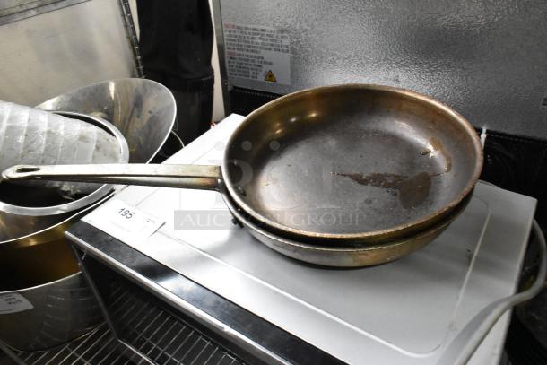 Nine assorted pots, including skillets and saucepans, shown with worn and tarnished exteriors. Includes auction tag 195.