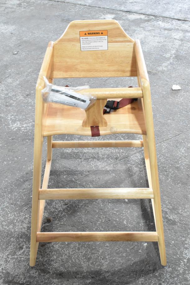 Wooden high chair with light finish, safety harness, warning label, and included assembly hardware. Good condition.