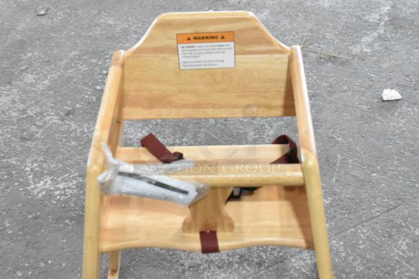 Wooden high chair with safety straps. Natural finish, includes warning label. Gently used condition.