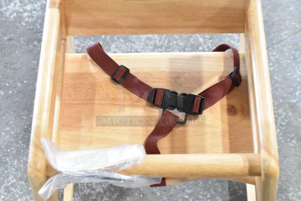 Wooden high chair with maroon safety strap, natural finish; 21 chairs available; excellent condition.