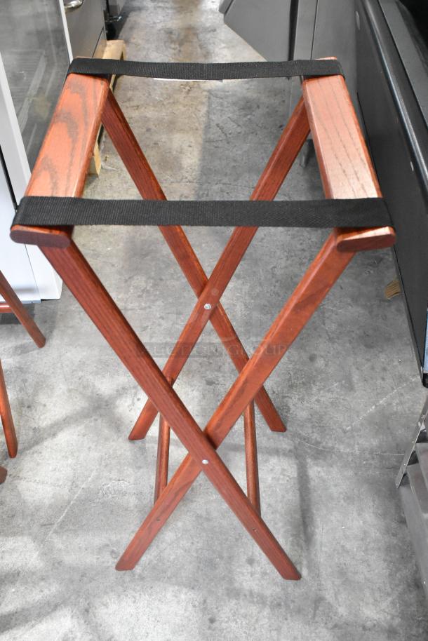 Four wooden folding serving tray stands, durable construction, sleek design, excellent condition, black fabric straps.