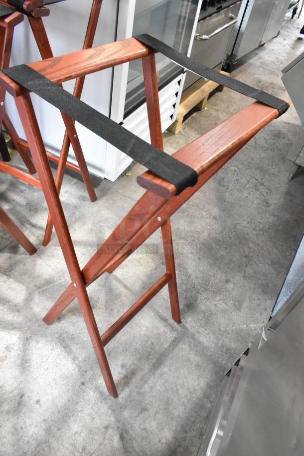 Four wooden folding serving tray stands with black straps, in good condition.