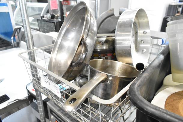 Stainless steel sauce pan, poly bus bin, various dishes in a metal basket with lot number tag. Mixed item kitchen lot.