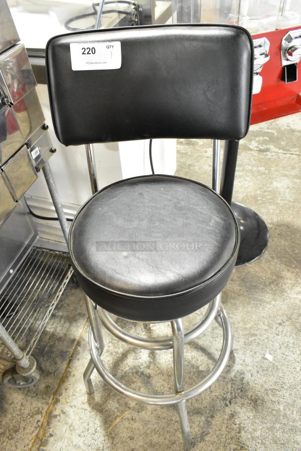 Black stool with backrest, metal frame, padded seat. Condition appears used. Auction tag reads "220, QTY 1".