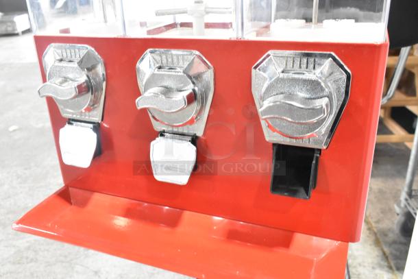 Red metal vending machine with three compartments and chrome coin mechanisms. Appears in good condition, suitable for small items.