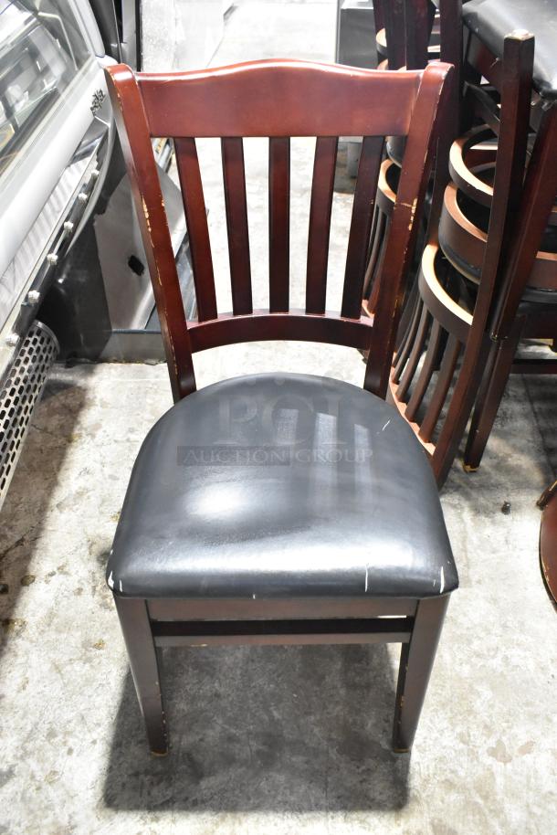 Wooden dining chair with black seat cushion, showing wear. Classic slat back design, brown finish. 14 available in auction.