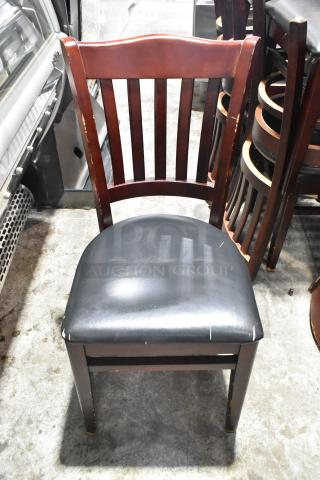 Wooden dining chair with black seat cushion, showing wear. Classic slat back design, brown finish. 14 available in auction.