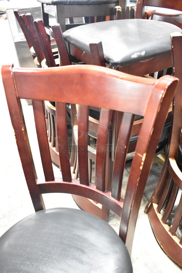 14 wooden dining chairs with black seat cushions, visible wear on wood, auction listing for 14x your bid.