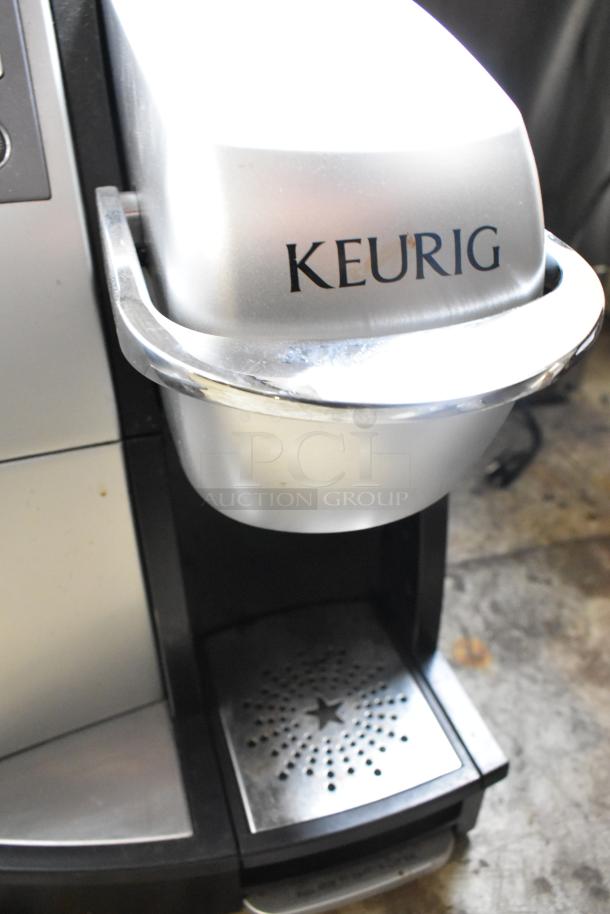 Keurig B3000SE Countertop Single Cup Coffee Machine, 120V, silver. Features drip tray and branded front. Slight wear visible.