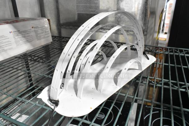 White metal arch structures with multiple loops, each perforated with holes, placed on a wire shelf.