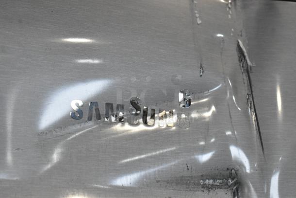 Samsung RZ11M7074SA stainless steel reach-in freezer with dents on surface. Visible Samsung logo. Model RZ11M7074SA. 115V, 1 phase.