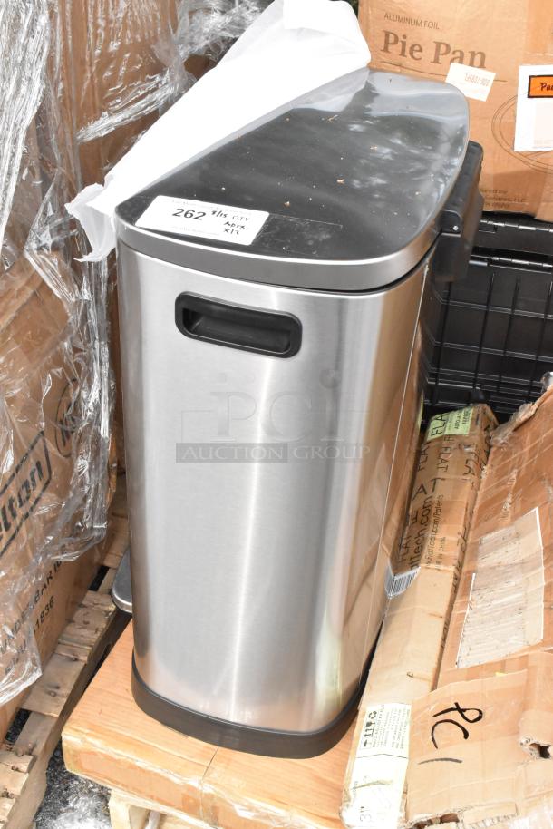 Stainless steel trash bin with black lid, new condition, atop wooden pallets; boxes labeled "Pie Pan" visible in background.