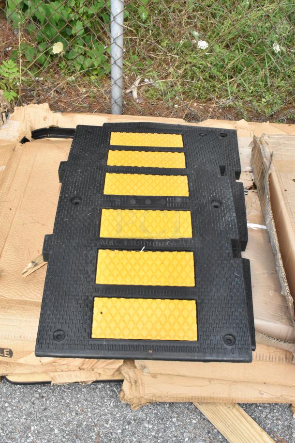 Black and yellow ramp section on damaged cardboard, outdoors near chain-link fence. Condition appears rugged.