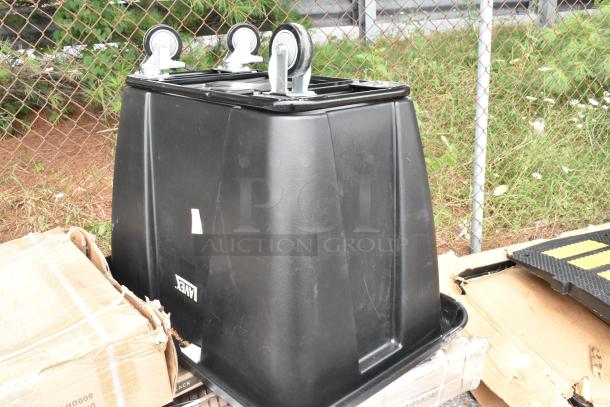 Black plastic utility bin with caster wheels, among boxed auction items. Marked "AMEX," showing signs of minor wear.