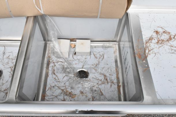 Brand new Regency 600S3242424S three compartment sink, 14-gauge stainless steel, with slight scratches and debris, 124" with drainboards.