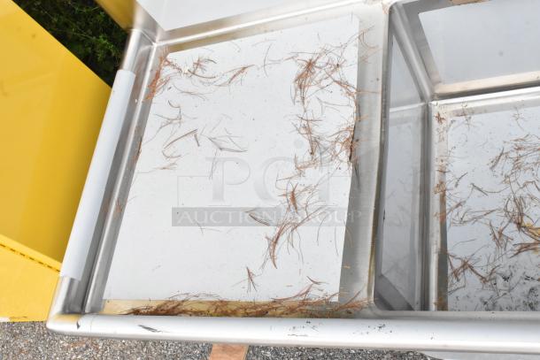 Brand new Regency 600S3242424S 124" stainless steel sink, three compartments, two drainboards, visible scratches, and debris.
