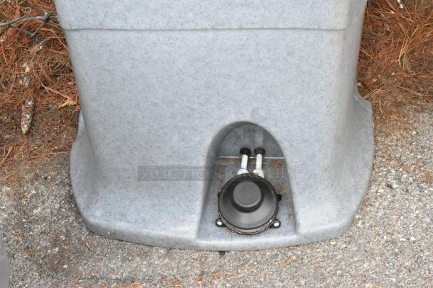 Brand new Lavex gray metal portable sink, scratch and dent condition, detailed view of base with two pipes and a plug.