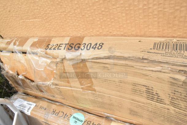 Damaged boxes of Lancaster 24"x24" copper bar height outdoor tables, marked 522ETSG3048, visible barcode and labeling.