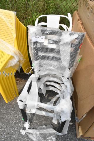 Four new scratch and dent chairs: two black metal ladder-back, two white Tolix style, wrapped in bubble wrap, label visible.