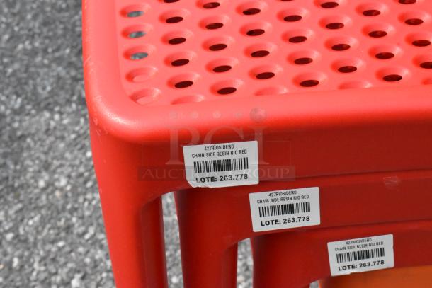 Red resin side chair with perforated seat, labeled "427RIOSIDERD" and "LOT: 263.778." New, scratch and dent condition.