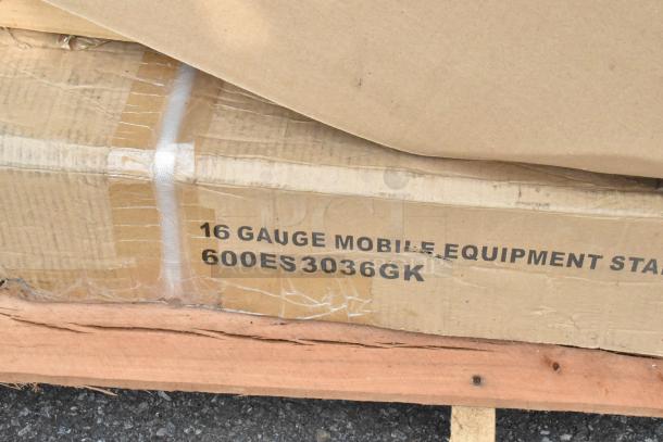 Cardboard box labeled "16 Gauge Mobile Equipment Stand 600ES3036GK" on wood pallet, indicating Regency stainless steel stand.